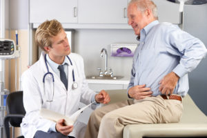 Male Doctor Examining Male senior Patient With Hip Pain