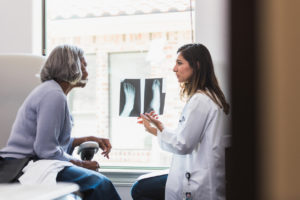 An orthopedic doctor reviewing some x-rays with a female patient and discussing treatment options. .