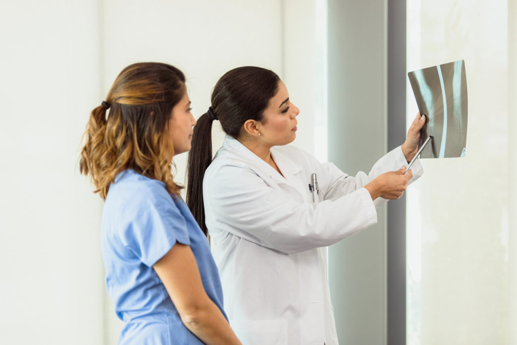 An orthopedic surgeon and a physician are discussing the results of a patient's x-ray.