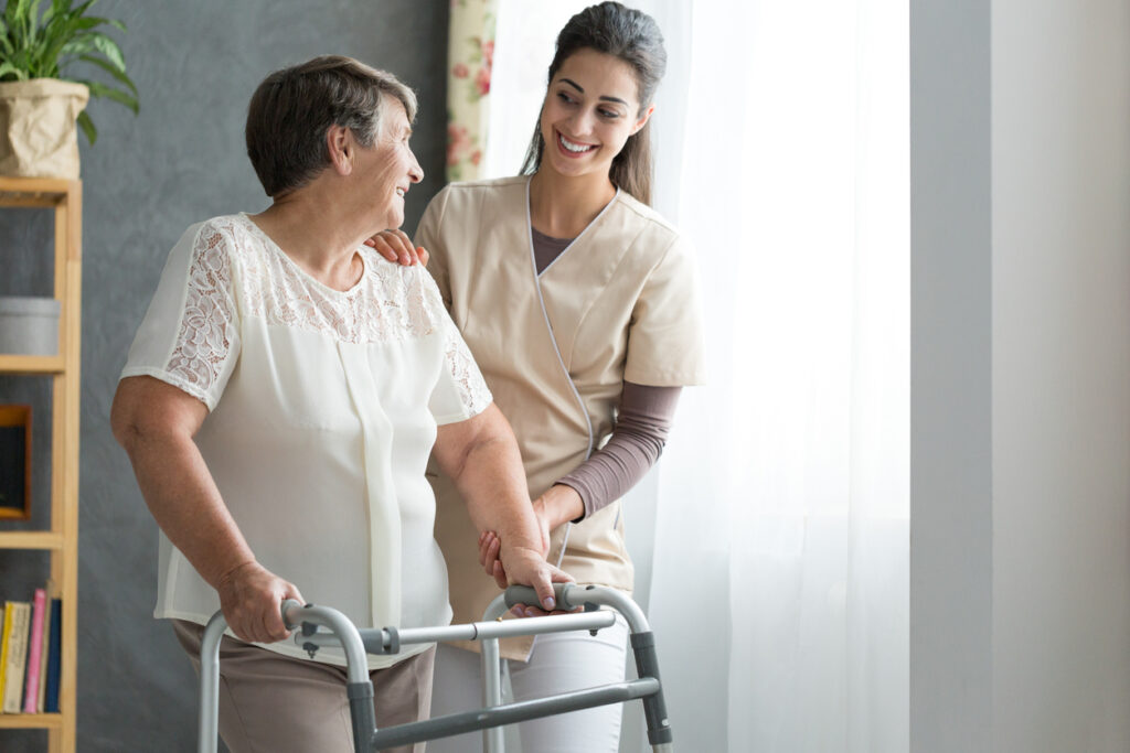 Nurse help senior person in walking after hip replacement surgery