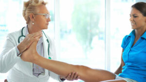 Closeup side view of mid 50's female doctor examining an ankle of mid 20's athlete woman. This is a typical sports injury.