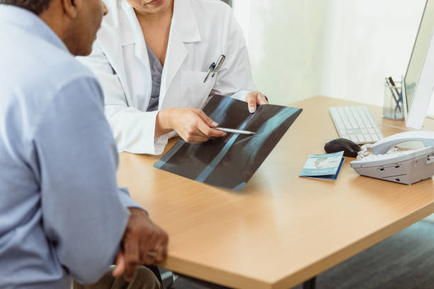 A female doctor points out something on an x-ray while discussing the findings with a male patient.