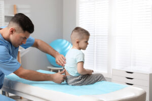Orthopedist examining child's back in clinic