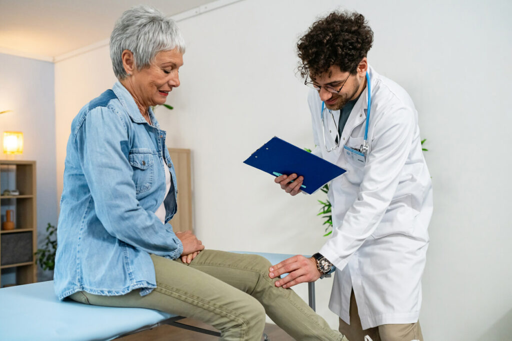 Orthopedisc doctor examining senior female patient's knee
