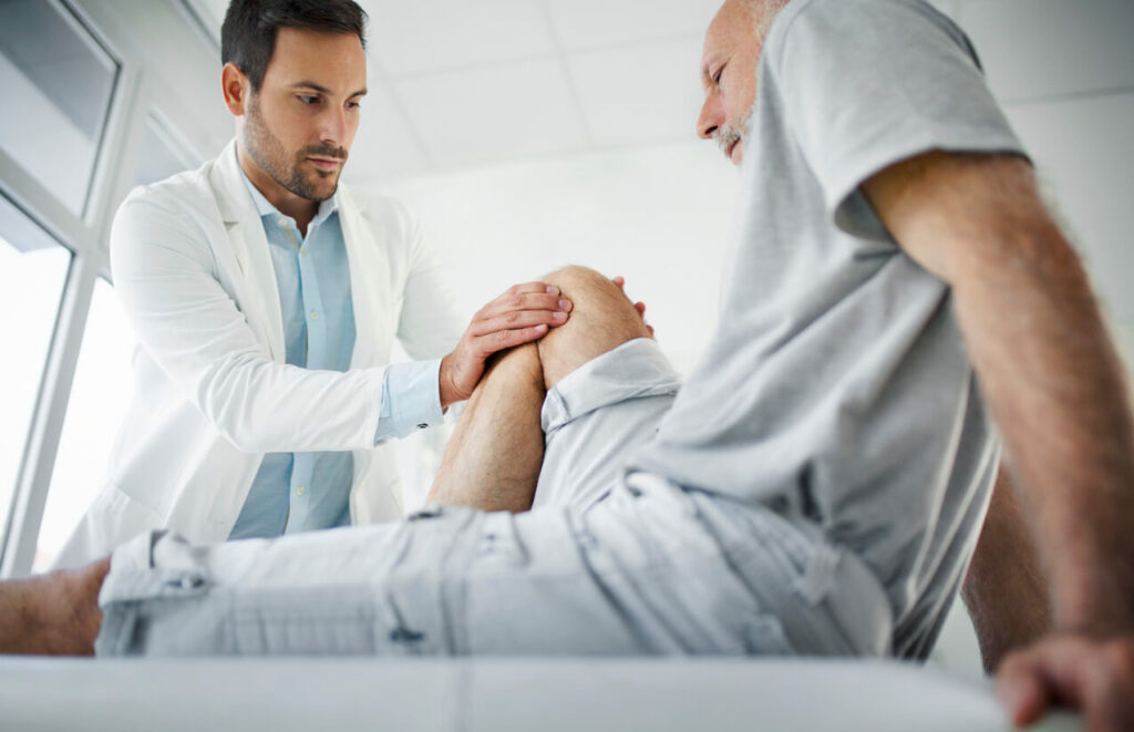 Orthopedic Surgeon examining patient's knee to help manage his arthritic pain.