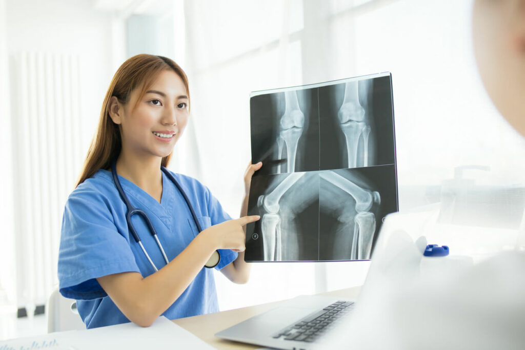 A young female doctor is explaining the x-ray results of an osteoarthritis diagnosis to her patient.