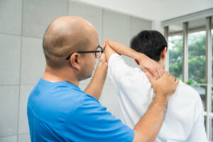 A male orthopedic surgeon treats a patient with a dislocated shoulder at an orthopedic clinic.