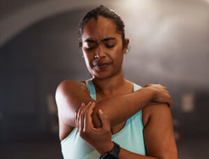 Shot of a young woman experiencing pain from an elbow fracture while working out in a gym.