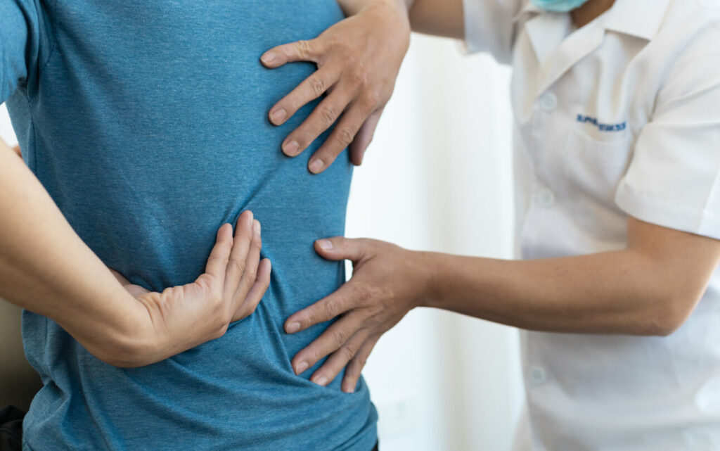 The orthopedic doctor is diagnosing the male patient's back pain in search of appropriate treatment.