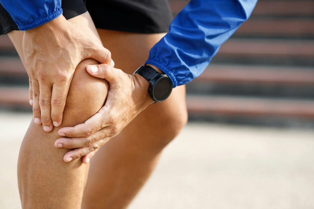 A runner is experiencing knee pain while running on a track.