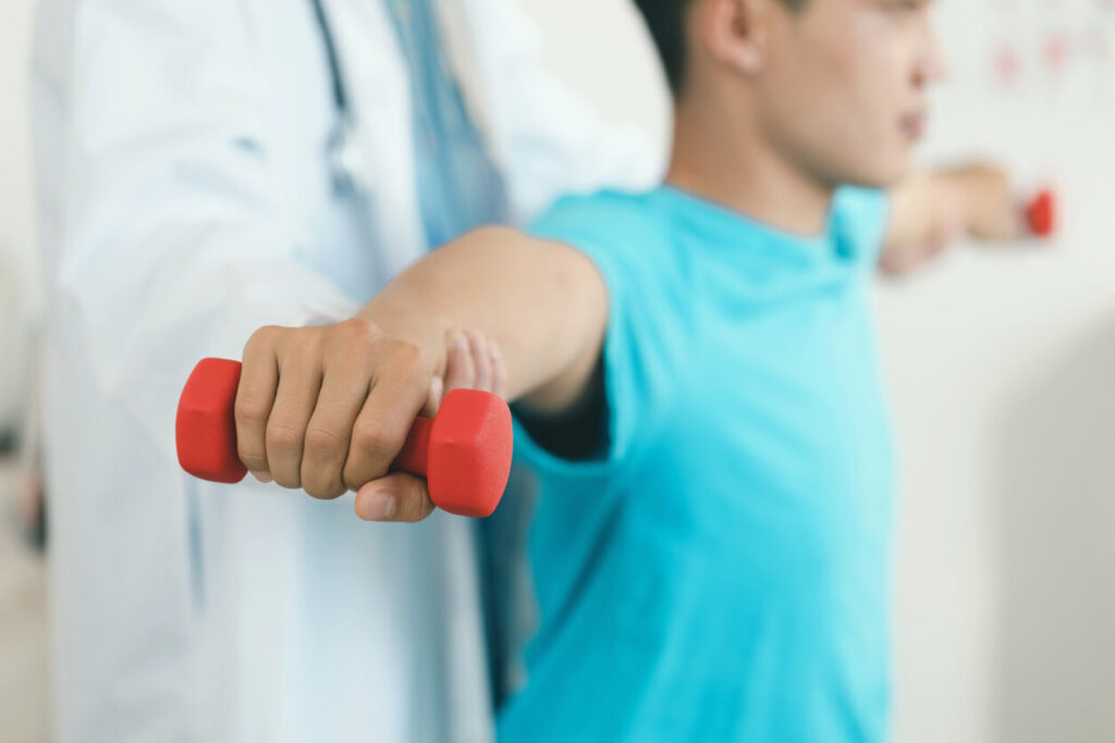An image shows a patient in physiotherapy with a sports medicine doctor performing physical exercises to recover from shoulder pain.
