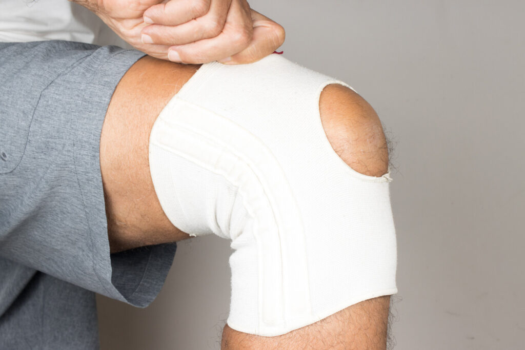 A man is wearing an ace bandage on his knee to treat an unstable kneecap.