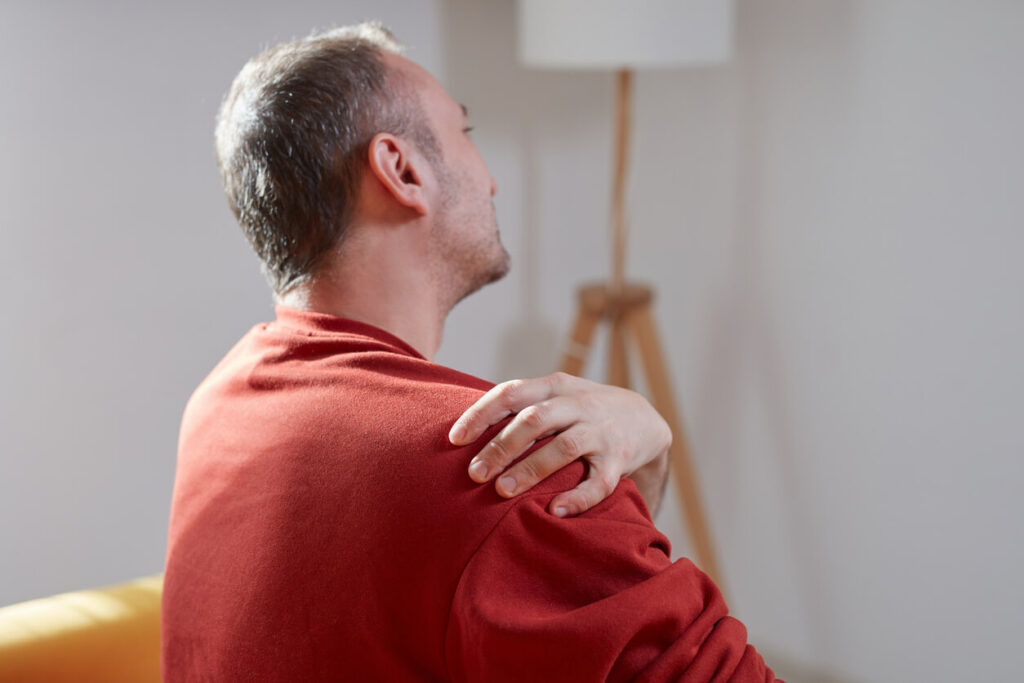 A man with shoulder pain at home due to broken collarbone.