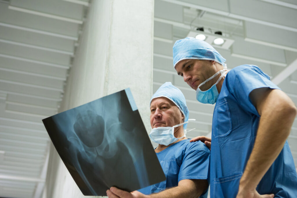 Male orthopedic surgeons examining x-ray of a patient's hip.