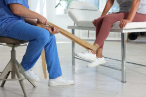 An orthopedic doctor assisting a patient experiencing arthritis pain during a rehabilitation session in a clinical care center.
