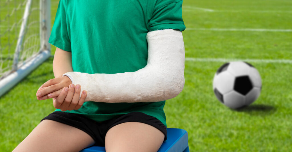 Child soccer player suffering broken hand fracture at the field.